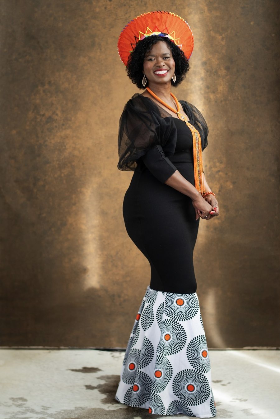 Tae Betty in zeremonieller Kleidung mit orangefarbenem Kopfschmuck